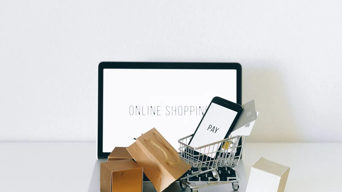 Laptop, điện thoại và giỏ hàng mini trên bàn bán hàng online