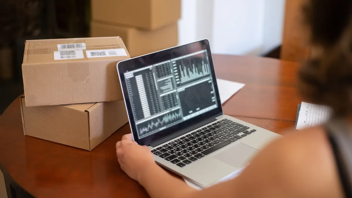 Tay dán băng keo thùng hàng cạnh laptop