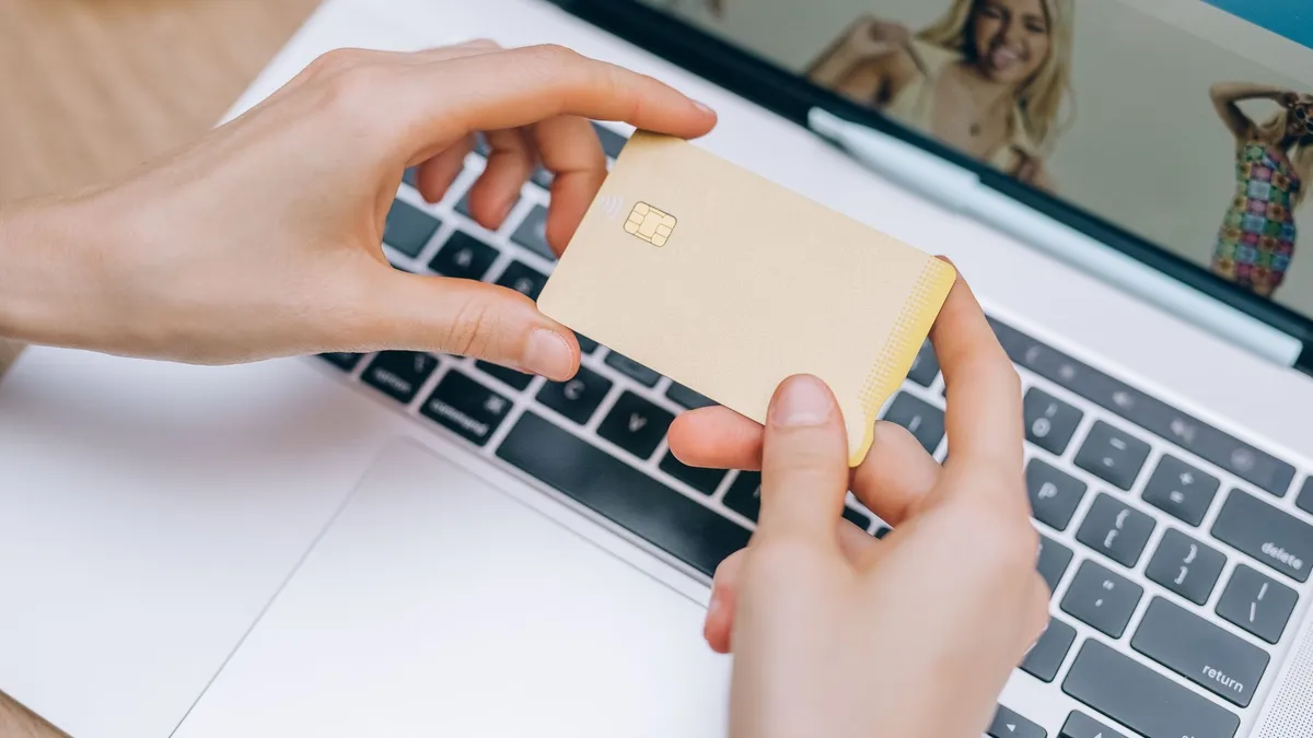 Tay cầm thẻ ngân hàng trước laptop khi thanh toán online