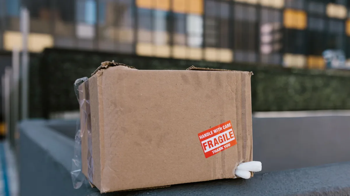 Hộp carton có nhãn cảnh báo hàng dễ vỡ đặt trên mặt bàn